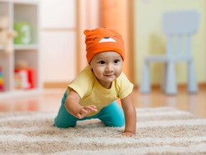 ¿A los cuántos meses gatea un bebé? Bebé gateando sobre alfombra.