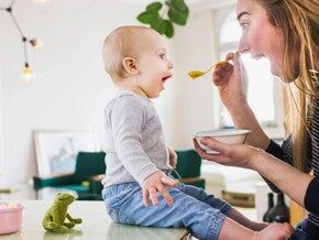 ¿Para qué sirven los probióticos? Mamá alimentando con una cuchara a su hijo pequeño con probióticos.