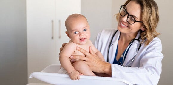 Conoce que es la curva de crecimiento y desarrollo Doctora revisando el crecimiento y desarrollo del bebé.